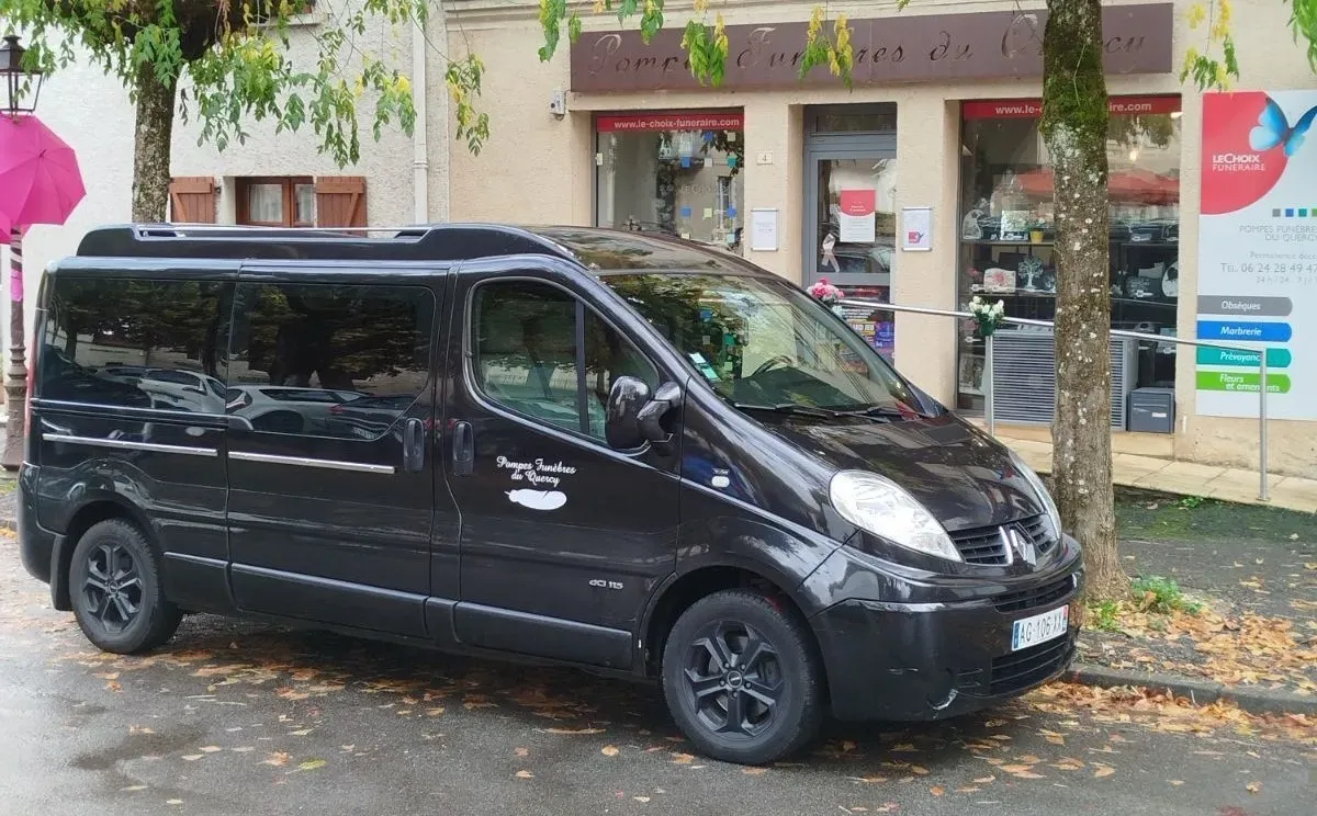 Corbillard noir stationné devant l'agence des pompes funèbres.