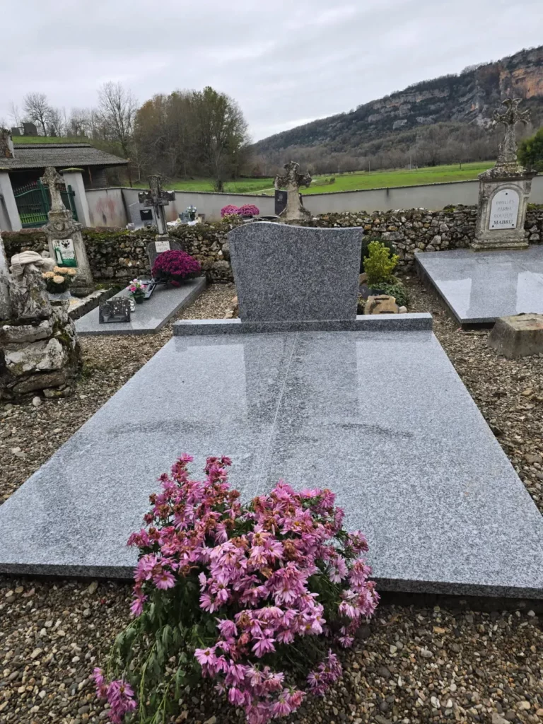 Monument funéraire en granite gris fleuri posé dans un cimetière.