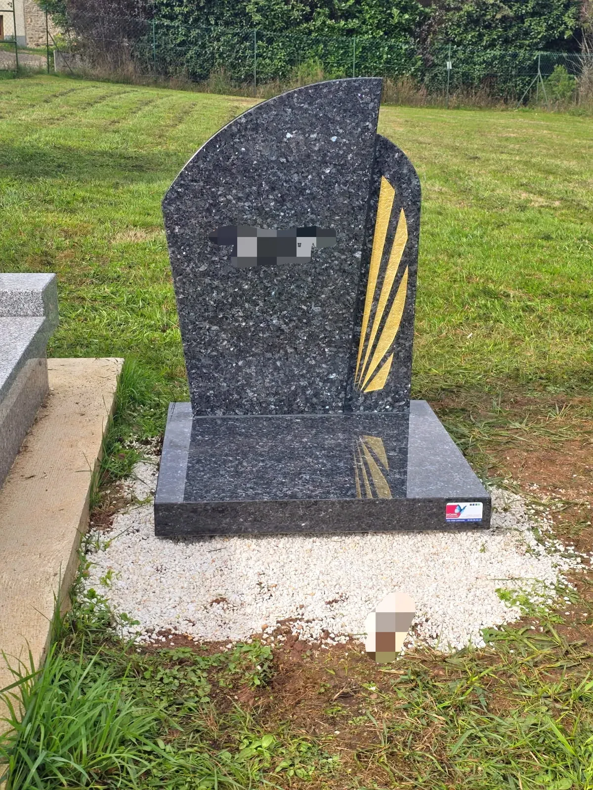 Stèle funéraire moderne en granite sombre ornée de dorures.