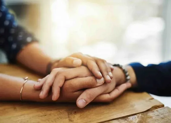 Mains de deux personnes serrées l'une dans l'autre pour réconforter.