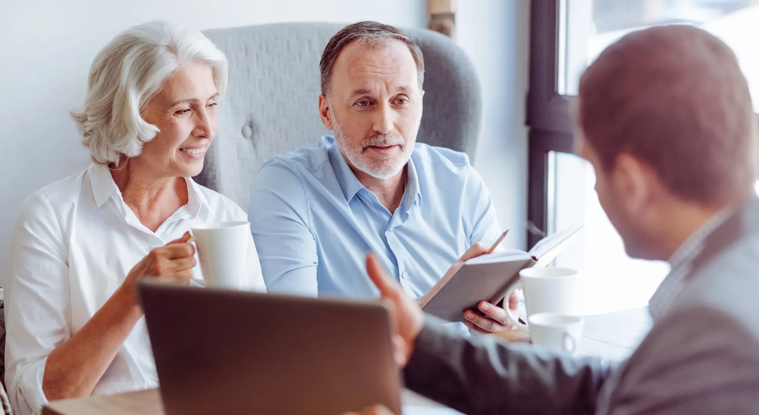 Couple senior en discussion avec un conseiller en assurance obsèques.